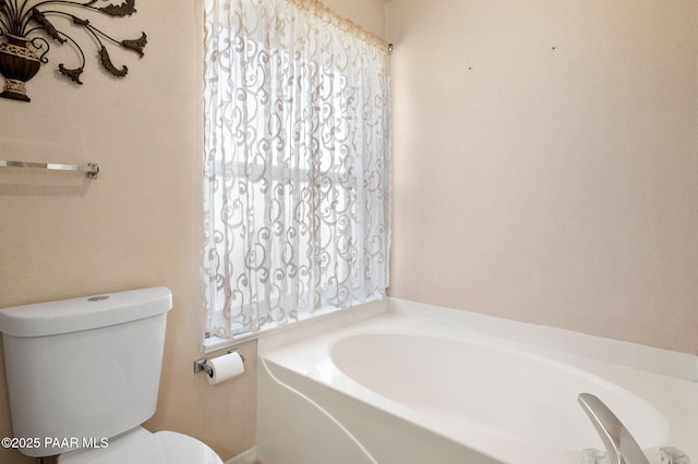 bathroom featuring a garden tub and toilet