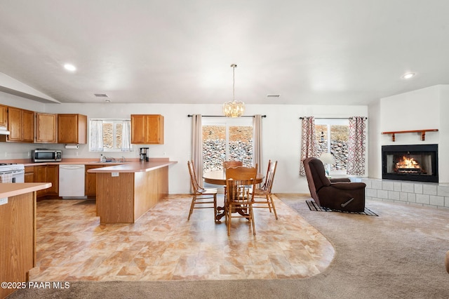 kitchen with open floor plan, a peninsula, white appliances, and light countertops