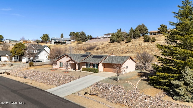 view of front of property with driveway, a garage, solar panels, a residential view, and a chimney