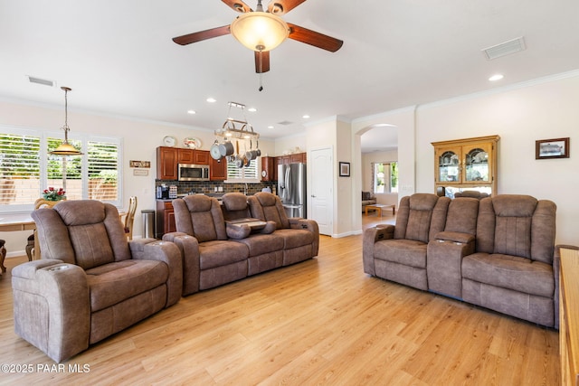 7812 E Rusty Spur Trl, Prescott Valley, AZ 86315 - living area featuring light wood-style flooring, arched walkways, a ceiling fan, ornamental molding, and plenty of natural light