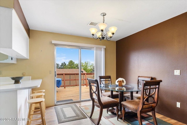 dining area with an inviting chandelier, light wood-style flooring, and visible vents