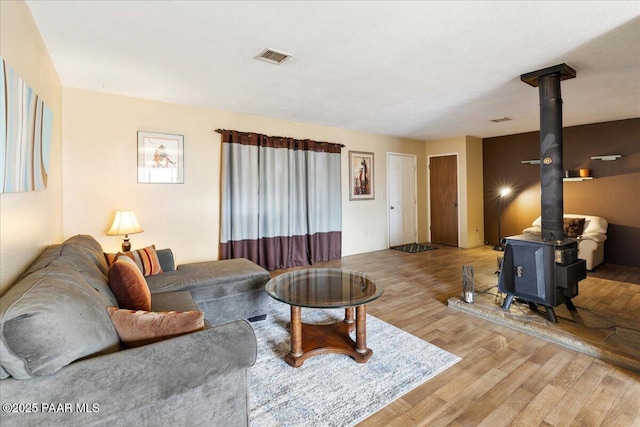 living area featuring a wood stove, visible vents, and light wood finished floors