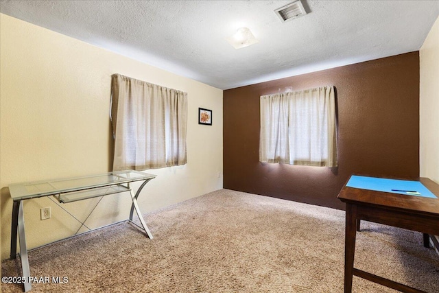 unfurnished office featuring carpet floors, a textured wall, a textured ceiling, and visible vents