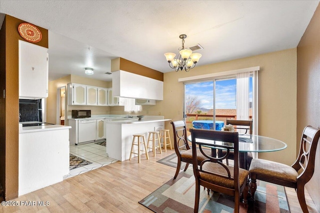dining room with visible vents, light wood-style flooring, and a notable chandelier