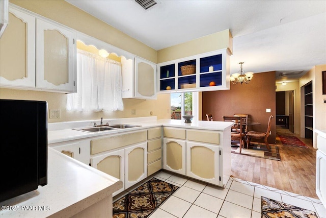 kitchen featuring a sink, a peninsula, a notable chandelier, and light countertops