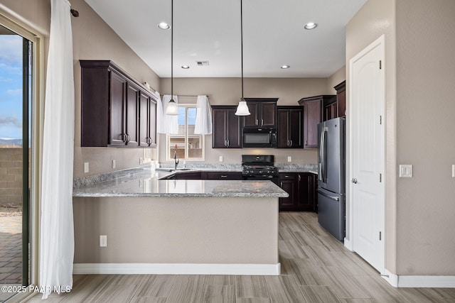 kitchen with dark brown cabinets, black appliances, a peninsula, and a sink