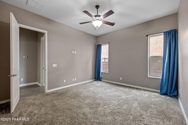 unfurnished room featuring a wealth of natural light, visible vents, carpet, and a ceiling fan