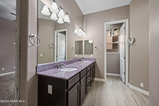 full bathroom featuring double vanity, baseboards, and a sink