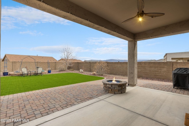 view of patio featuring ceiling fan, a grill, a fenced backyard, and an outdoor fire pit