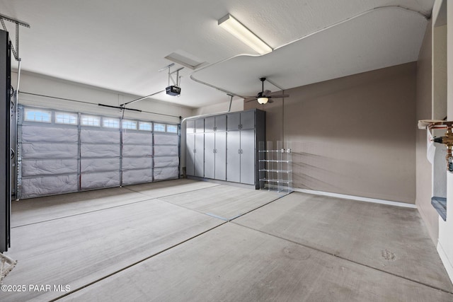 garage featuring baseboards, a garage door opener, and a ceiling fan