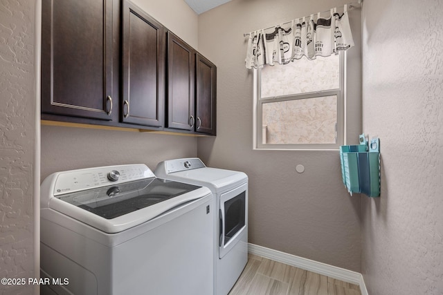 clothes washing area featuring light wood-type flooring, washer and dryer, cabinet space, baseboards, and a textured wall