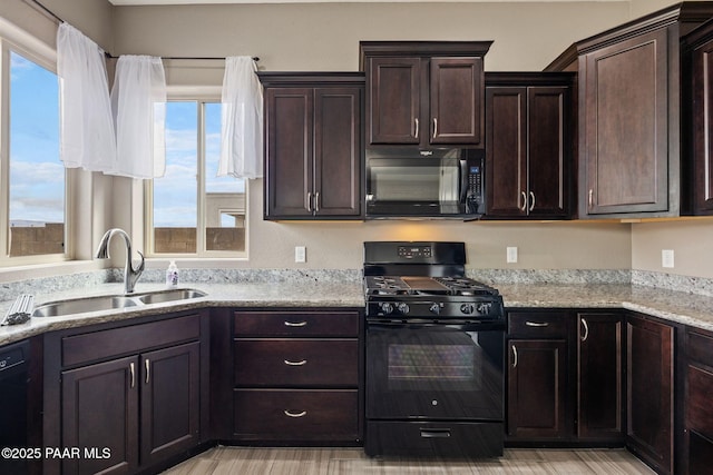 kitchen featuring a sink, light stone countertops, dark brown cabinetry, and black appliances