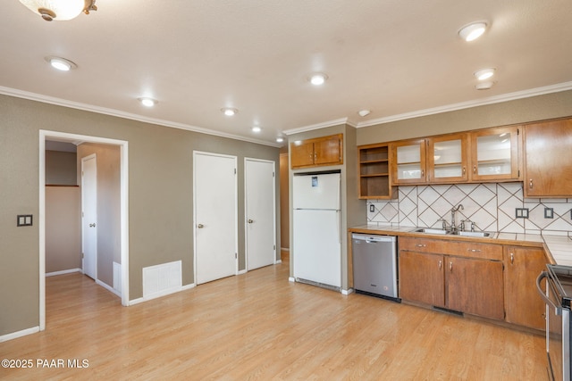 kitchen featuring dishwasher, range, white refrigerator, light hardwood / wood-style floors, and decorative backsplash