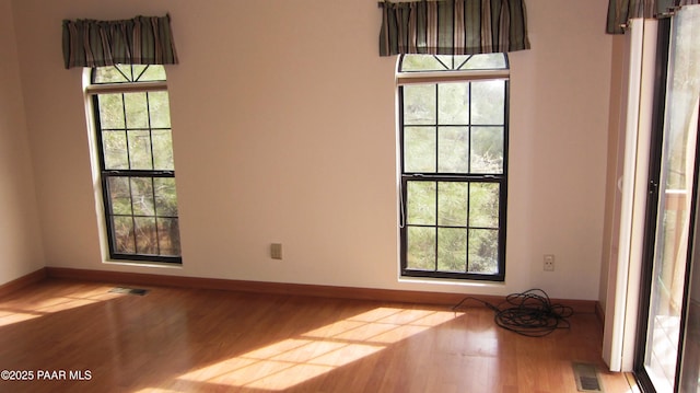 spare room with visible vents, baseboards, and wood finished floors