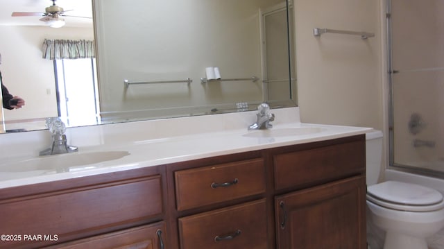 full bath with ceiling fan, a sink, toilet, and double vanity