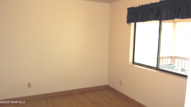 empty room featuring baseboards, a wealth of natural light, and wood finished floors