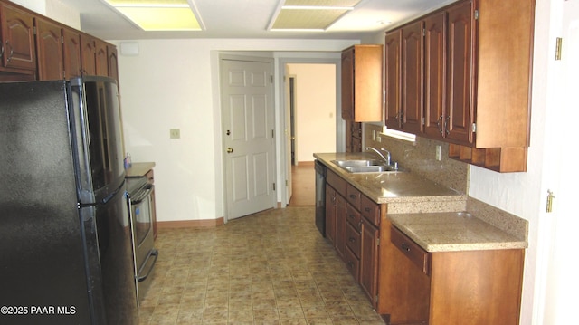 kitchen with light countertops, electric range, decorative backsplash, freestanding refrigerator, and a sink