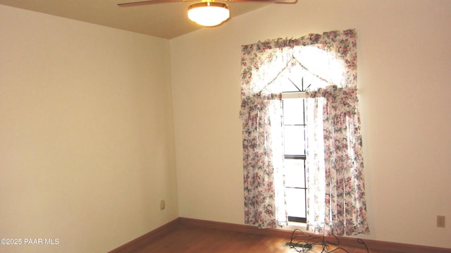 unfurnished room with baseboards, wood finished floors, a wealth of natural light, and a ceiling fan