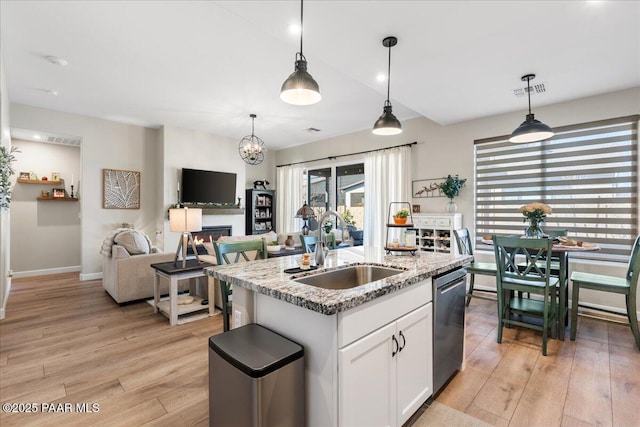 kitchen with a center island with sink, decorative light fixtures, dishwasher, white cabinets, and sink