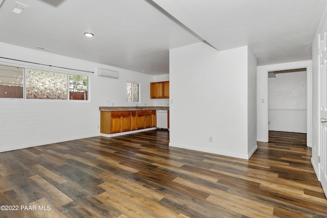 unfurnished living room with an AC wall unit, sink, and dark hardwood / wood-style floors