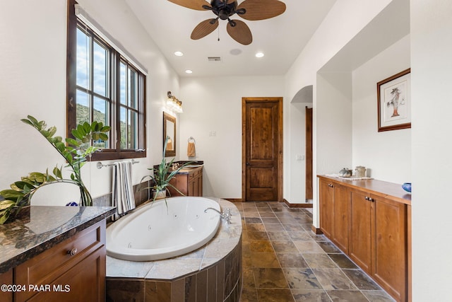 bathroom featuring vanity, a relaxing tiled tub, and ceiling fan