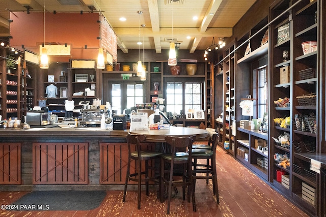 interior space featuring hardwood / wood-style floors, beam ceiling, and hanging light fixtures