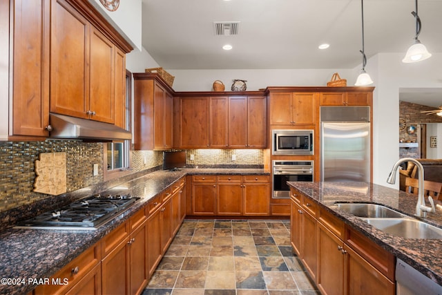 kitchen featuring pendant lighting, sink, built in appliances, ceiling fan, and tasteful backsplash