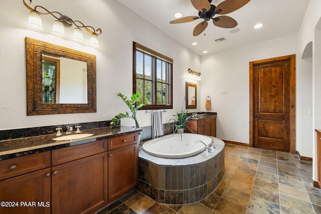 bathroom with vanity, ceiling fan, and tiled tub