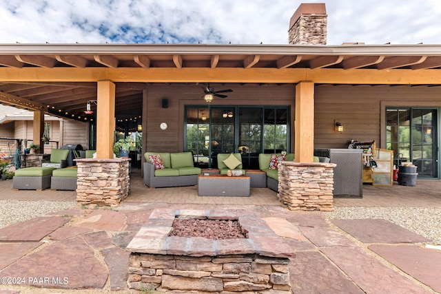 view of patio / terrace featuring ceiling fan and an outdoor living space with a fire pit