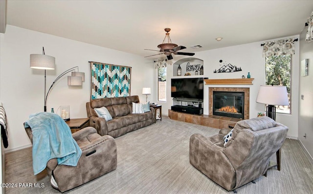 carpeted living room with a tile fireplace and ceiling fan