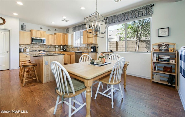 dining space featuring dark wood-type flooring, sink, and a notable chandelier