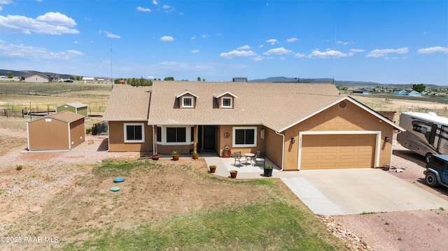 26455 N Bull Snake Rd, Paulden, AZ 86314 - view of front of home featuring an attached garage, driveway, stucco siding, and a storage shed