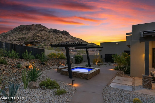 patio terrace at dusk with an in ground hot tub and a mountain view