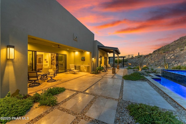 back house at dusk featuring a mountain view, a patio area, and ceiling fan