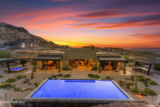 pool at dusk with a mountain view and a patio area