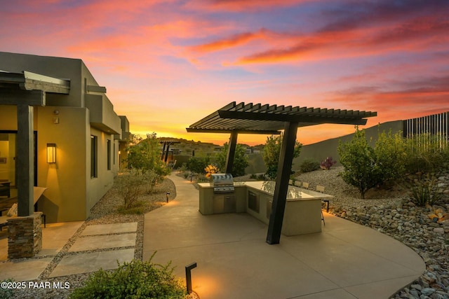 patio terrace at dusk with area for grilling and an outdoor kitchen