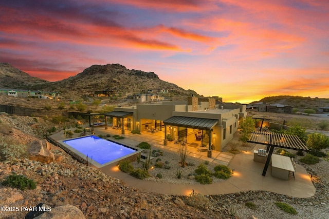 pool at dusk with a mountain view and a patio area