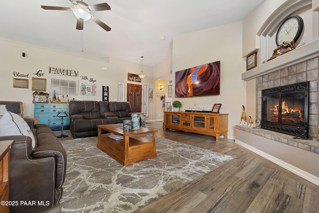 5570 N Pierce Ln, Prescott Valley, AZ 86314 - living area featuring a ceiling fan, wood finished floors, a tile fireplace, arched walkways, and baseboards