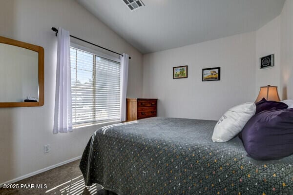 carpeted bedroom featuring baseboards, lofted ceiling, and visible vents