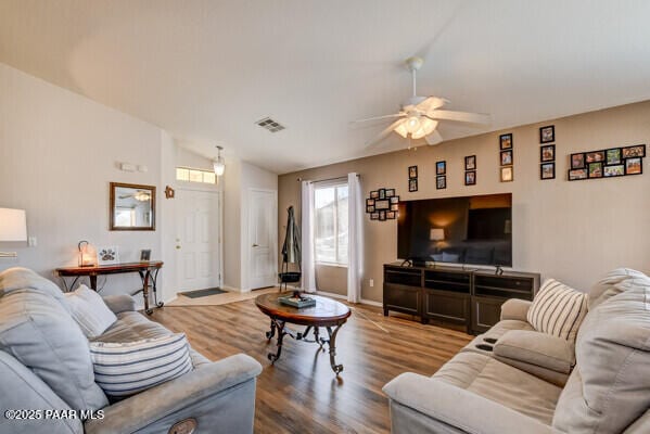 living room featuring lofted ceiling, baseboards, visible vents, ceiling fan, and wood finished floors