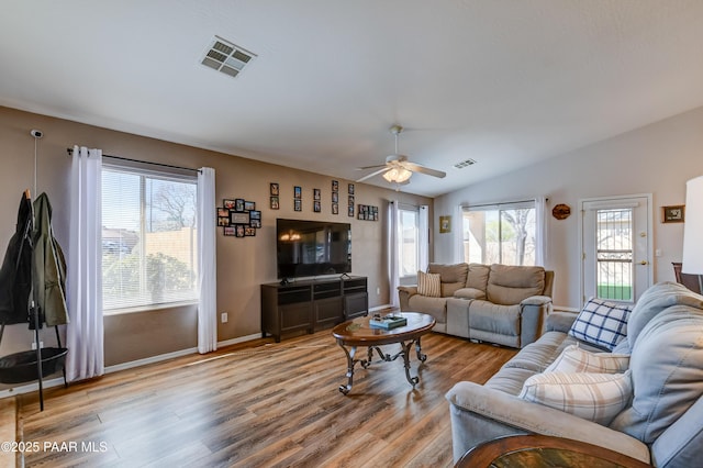 living area featuring ceiling fan, light wood-style floors, vaulted ceiling, and visible vents