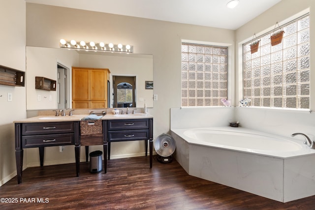 full bath featuring a bath, a wealth of natural light, wood finished floors, and vanity