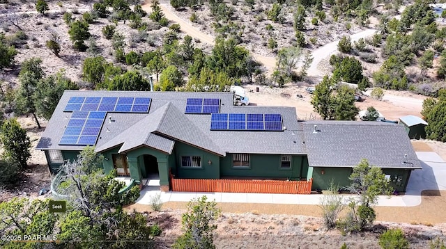 view of front of property featuring solar panels and roof with shingles
