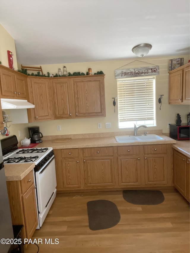 54683 N El Portal Ln, Seligman, AZ 86337 - kitchen featuring under cabinet range hood, light countertops, white gas range oven, light wood-style flooring, and a sink