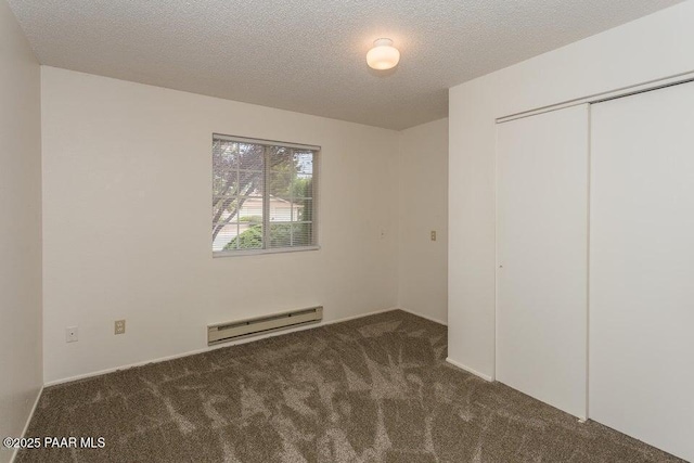 unfurnished bedroom with a baseboard heating unit, carpet floors, a textured ceiling, and a closet