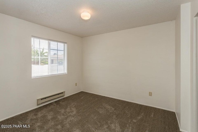 empty room with a baseboard heating unit, dark colored carpet, and a textured ceiling