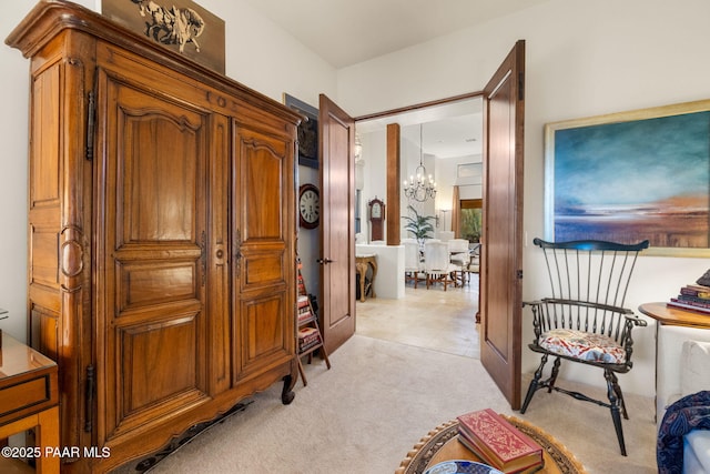 hall with light carpet and an inviting chandelier