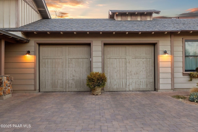 garage at dusk featuring decorative driveway