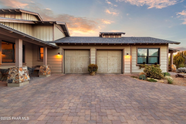 exterior space with a garage, a shingled roof, and decorative driveway