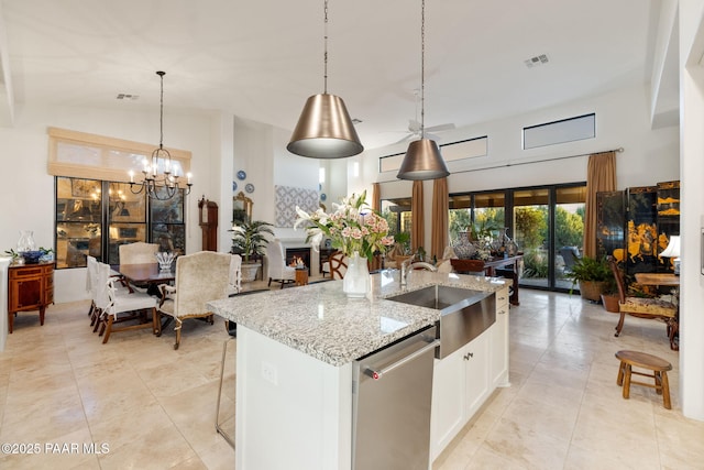 kitchen with light stone counters, stainless steel dishwasher, white cabinetry, a sink, and an island with sink